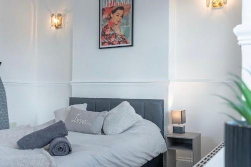ein weißes Bett mit Kissen und einem Bild an der Wand in der Unterkunft La Casa de Class - Luxury & Comfort in Cardiff