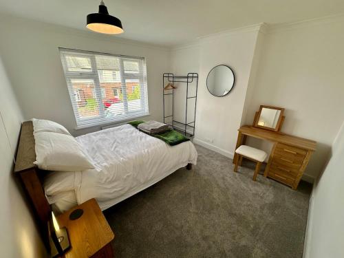 a bedroom with a bed and a desk and a window at 4 Bedroom House, En-Suite, 3 Doubles 1 Single, 2 Car Parking in Colchester