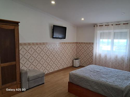 een slaapkamer met een bed en een tv aan de muur bij Casa Tio Mário in Fontinhas