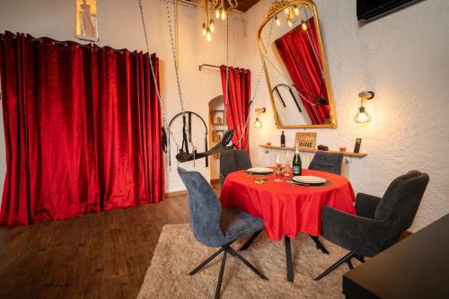 ein Esszimmer mit einem roten Tisch und Stühlen in der Unterkunft Le Confidentiel - Le Refuge de vos Désirs secrets in Sélestat