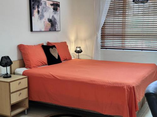 1 dormitorio con cama con sábanas de color naranja y ventana en Oasis Haven Curacao, en Willemstad