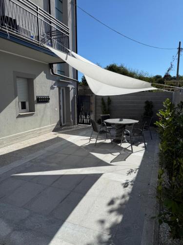 een patio met een tafel en stoelen onder een witte parasol bij Isidoro affittacamere in Carugo