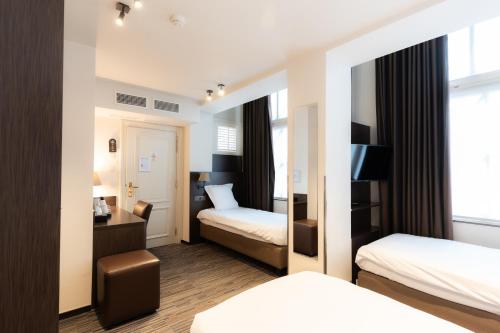 una camera d'albergo con due letti e una scrivania di Golden Tree Hotel a Bruges