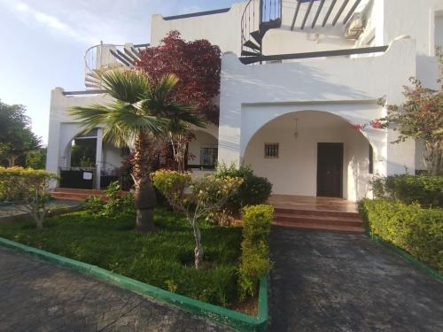 a white house with a palm tree in the yard at Super villa de haut standing in Dar Merah Deriba