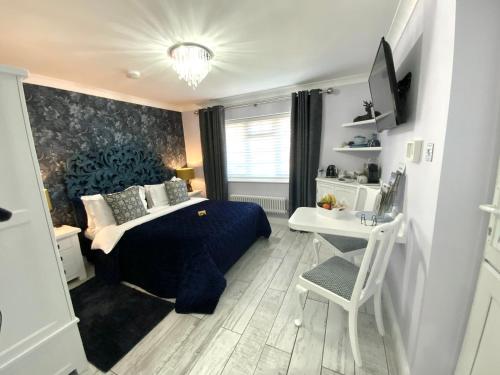 a bedroom with a blue bed and a desk at THE KNIGHTWOOD OAK a Luxury King Size Bed -En-Suite Space - LYMINGTON NEW FOREST with Private Entrance - Key Box entry-Free Parking & Private Outdoor Seating Area -Full Fibre WiFi -Town ,Shops , Pubs & Solent Way Walking Distance & Complimentary Breakfast in Lymington