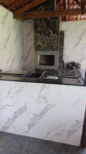 uma cozinha com uma bancada em mármore e uma lareira em Chacara Sossego em Monte Sião