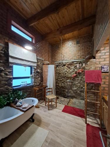 a bathroom with a tub and a stone wall at Helpmekaar Farm in Kareedouw