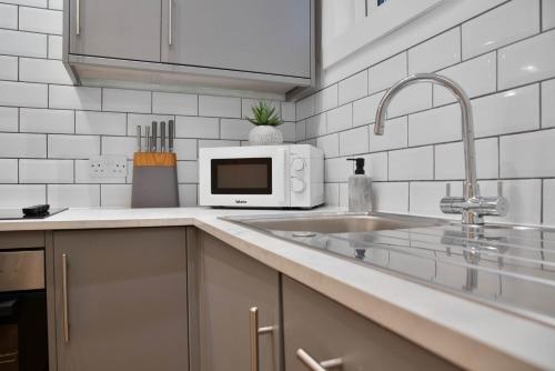 a white kitchen with a sink and a microwave at WhiskAwayHomes - St Stephens Court - Apartment 2 in Henwick