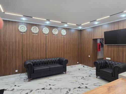 ein Zimmer mit zwei schwarzen Ledersofas und einem Flachbildfernseher in der Unterkunft Kazakhstan-hostel in Astana