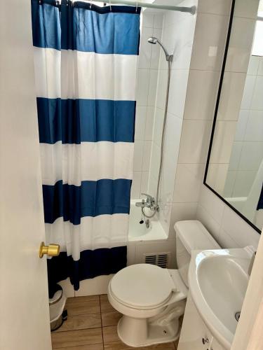 a bathroom with a blue and white shower curtain and a toilet at Departamento Borde Mar in Coquimbo