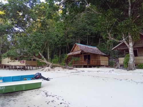 a boat on the beach with a hut in the background at Wobbegong Raja Ampat in Yennanas Besir