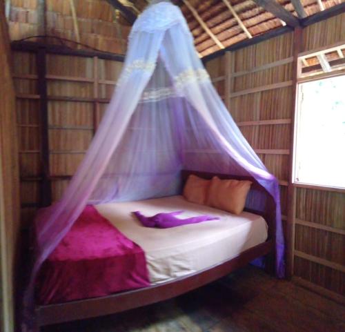 a bed in a room with a mosquito net at " Wobbegong Raja Ampat " in Yennanas Besir