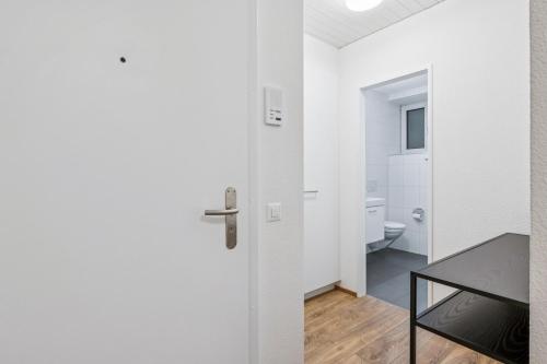 a white bathroom with a toilet and a door at Luxury 1BR in the city center - Color 5 in Zürich