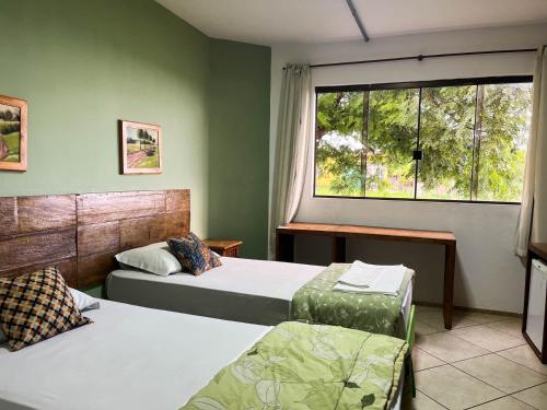 a bedroom with two beds and a window at Hotel Catavento in Cristalina