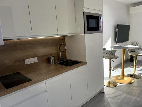 Cap d'Ail - Studio - Terrace with sea view - Malabo في كاب دايل: مطبخ بخزائن بيضاء ومغسلة