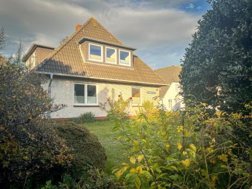 a house with a gambrel roof in a yard at Eldorado Ferienwohnungen in Norddorf