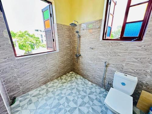 a bathroom with a shower and a toilet and a window at Vuga Hostel in Zanzibar City