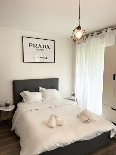 Un dormitorio con una gran cama blanca con dos toallas encima. en Studio moderne à 10 minutes de Paris avec jardin privé, en Romainville