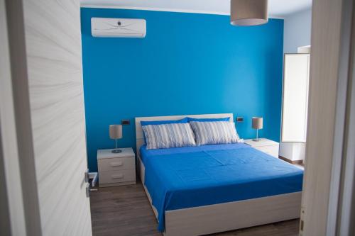 a blue bedroom with a bed with a blue wall at Enjoy Home in Acitrezza