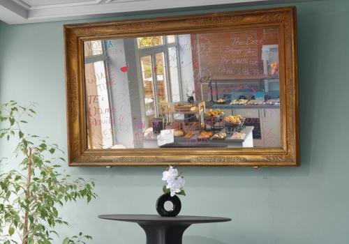a mirror hanging on a wall with a table with flowers at Trip Inn Hotel Egelsbach Frankfurt in Egelsbach