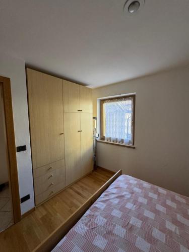 an empty bedroom with a bed and a window at Appartamento Fontane in Panchia