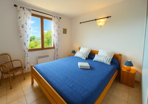 Un dormitorio con una cama azul y una ventana. en Villa la Baume, en Quinson