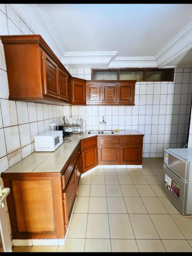 a kitchen with wooden cabinets and a tiled wall at Résidences hôtelières Micheline et Emile BASTOS in Yaoundé