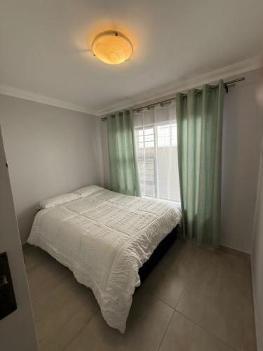 a bedroom with a bed with a window and a light at Da Silva Apartment in George