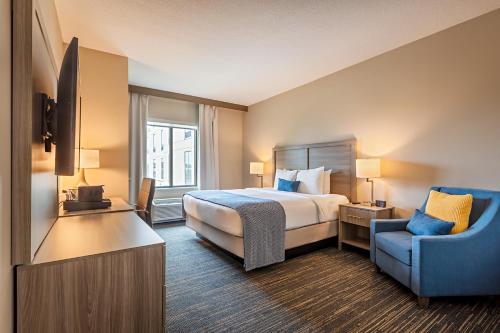 a hotel room with a bed and a blue chair at Pestana Orlando Suites - Lake Buena Vista in Orlando