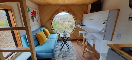 a tiny house with a blue couch and a round window at Casa Villa de leyva in Sáchica