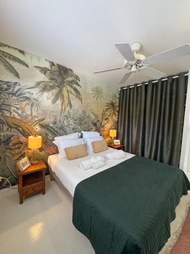 a bedroom with a large bed with a palm mural at Villa Vue Mer, piscine, proche de la plage et Golf Trois Ilets in Les Trois-Îlets