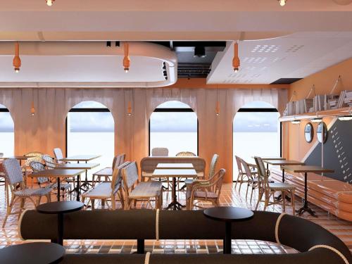 Un comedor con mesas y sillas y ventanas. en ibis Styles La Rochelle Centre les Minimes, en La Rochelle