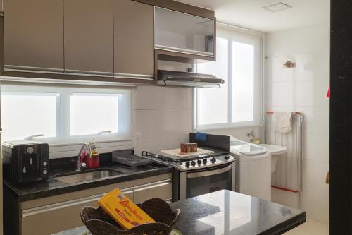 a kitchen with a sink and a stove top oven at Vista para as Montanhas in Guarapari