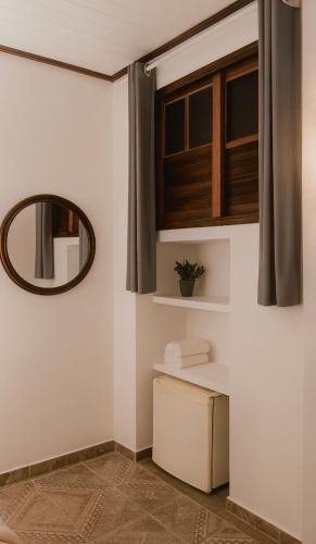 a bathroom with white walls and a mirror at Kalena Suítes in Lençóis