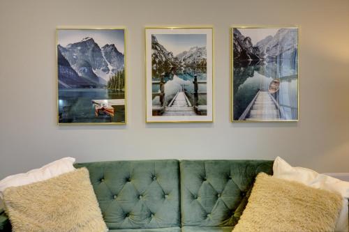 four pictures on a wall above a green couch at Portland Street Leamington Spa Apartments in Leamington Spa