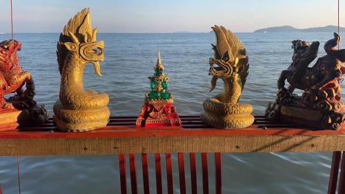 a group of statues sitting on a table near the water at Fisherman's house on stilts Phuket Old Town in Ban Tha Khreng