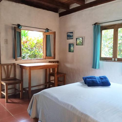 a bedroom with a bed and a desk and a window at Las Cabañas de la Iguana in Ayampe