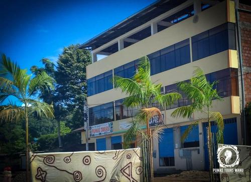 een gebouw met palmbomen ervoor bij Hinkiori Inn - Hotel Manu in Pillcopata