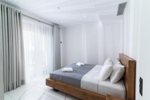 a white bedroom with a bed and a large window at Villa Melora in Pitsidia