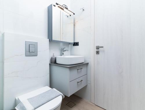 a white bathroom with a sink and a toilet at Villa Melora in Pitsidia