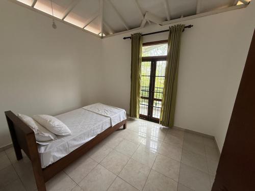 a bedroom with a bed and a large window at Ceylon Villa in Matara