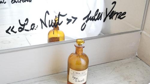 Una botella de vino en el suelo junto a un espejo. en La Nuit - Suite avec baignoire, en Nantes