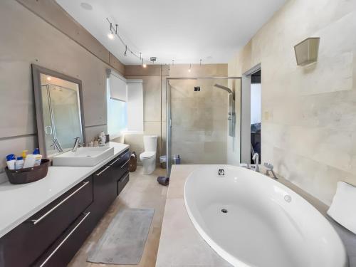 Un baño con una gran bañera blanca y una ducha. en Villa Capitán Modern Stay Near Beach with pool, en Vega Alta