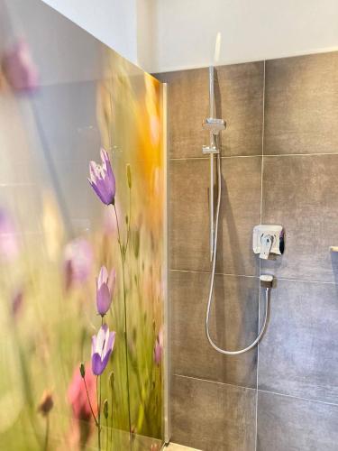 a shower with purple flowers painted on the wall at Appartements Blumenwiese in Ramsau am Dachstein