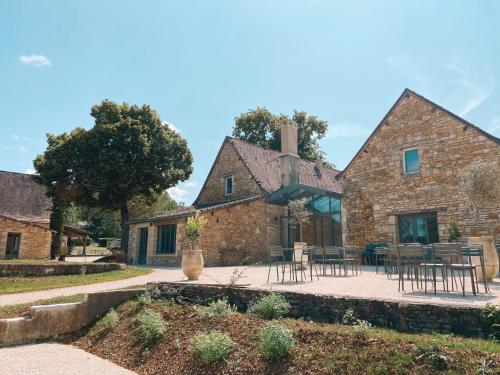 - une vue extérieure sur une maison en pierre dotée de tables et de chaises dans l'établissement Domaine St-Amand, à Saint-Amand-de-Coly