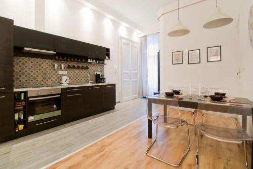 a kitchen with black cabinets and a table with chairs at Downtown Rising Sun 104 sq.m in Budapest