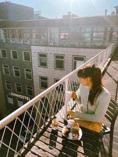 a woman sitting on a bench with food and drinks at Danhostel Aarhus City in Aarhus