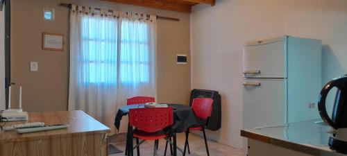 une cuisine avec une table, des chaises et un réfrigérateur dans l'établissement Piedrabuena Yenua, à Comandante Luis Piedrabuena