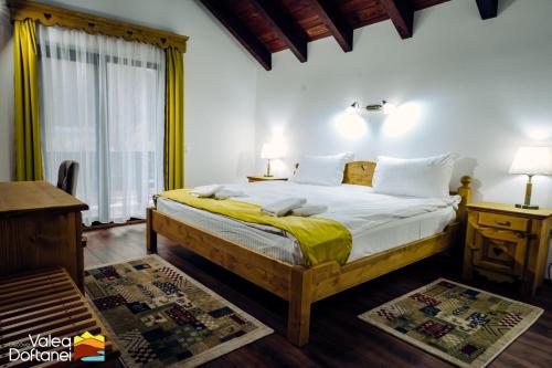 a bedroom with a large bed with a yellow blanket at Mai cu Mot Doftana Luxury Chalets in Trăisteni