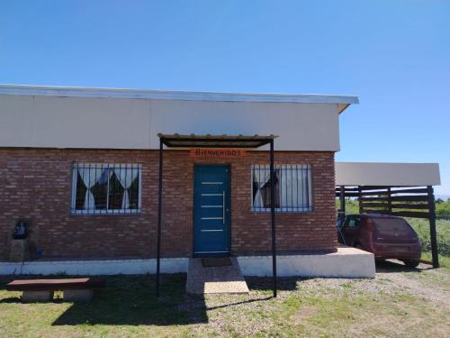 a brick building with a blue door and a car at Portal del Sol in Villa Yacanto
